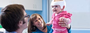 doctor, parent and baby using helmet therapy