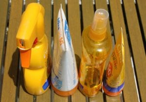 Multiple brands of sunscreen on a wooden deck