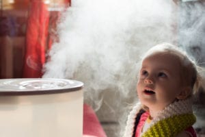 Child stairs in wonder at vapor produced by a humidifier. 