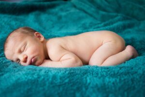 sleeping newborn on green blanket